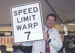 Gov. Miller Holding up SPEED LIMIT WARP 7 sign